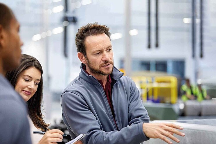 Ingenieur diskutiert mit Managern in einer Automobilfabrik.
